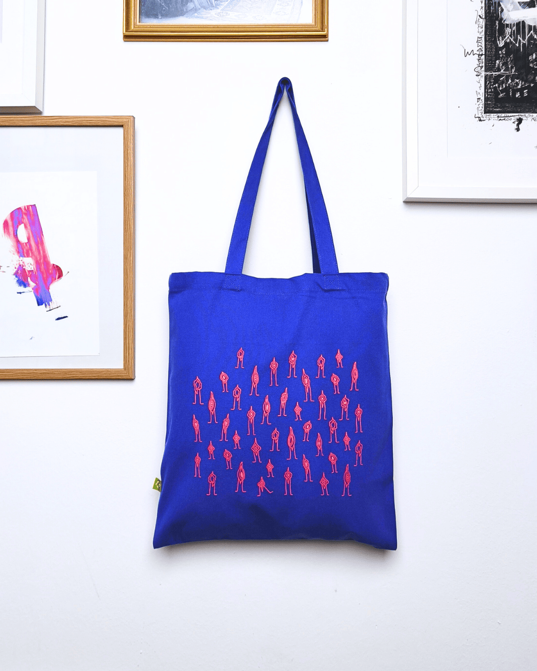 Eine blaue Tote Bag mit rosa vulven stark abstrahiert/line Art bedruckt.
