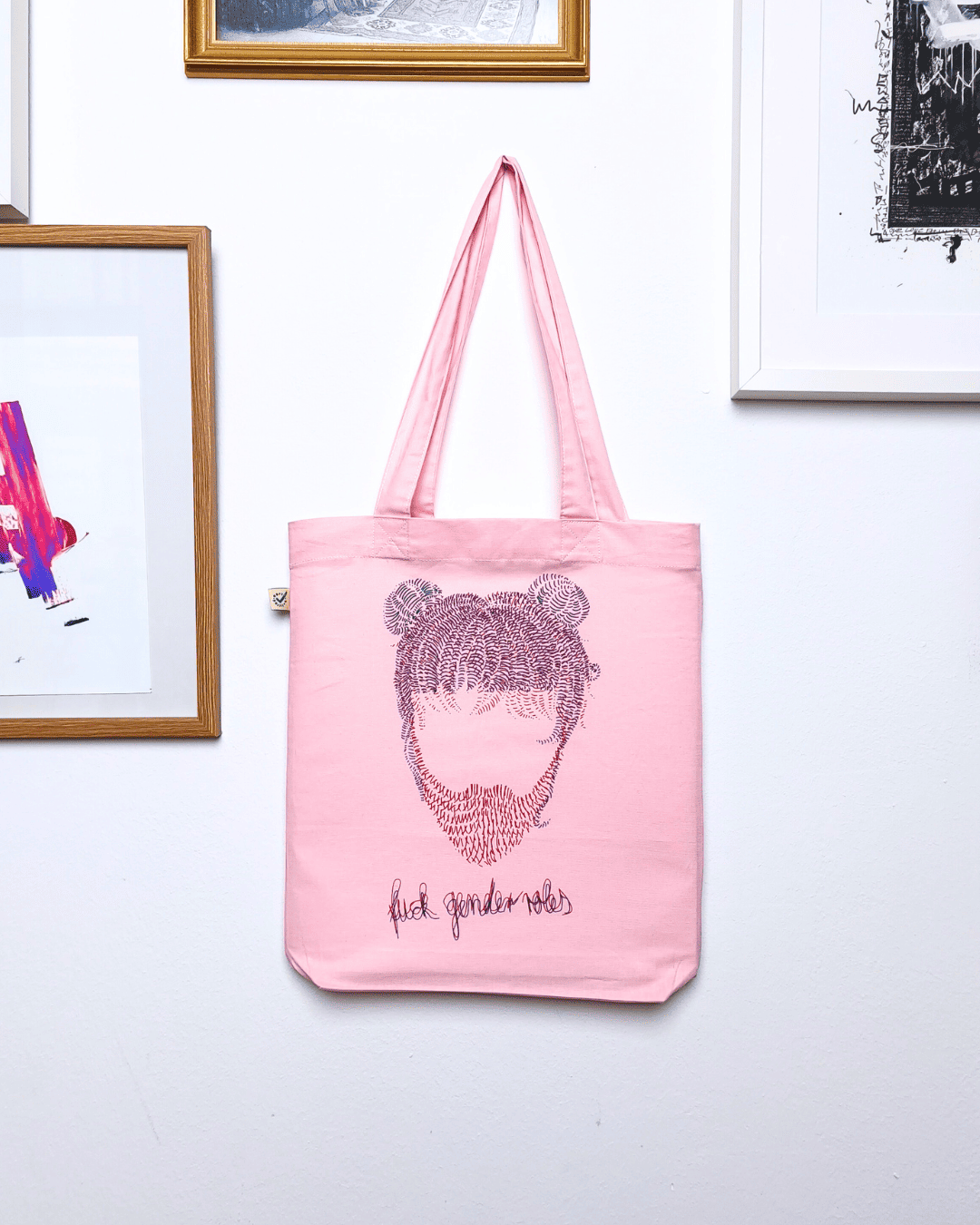 Eine rosa Tote Bag mit gestrichelter Frisur mit Bart abstrahiert/line Art bedruckt. Darunter steht fuck genderroles.